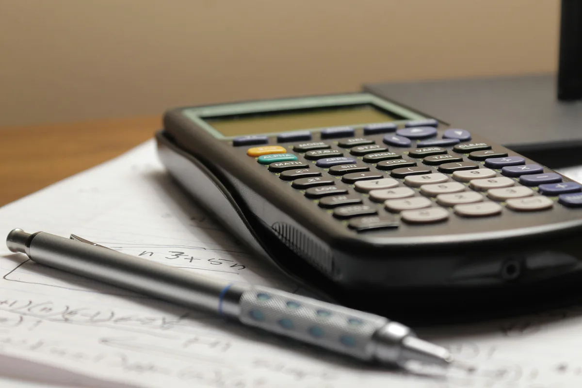 Calculator and pen on a receipt, representing tip and bill-splitting math